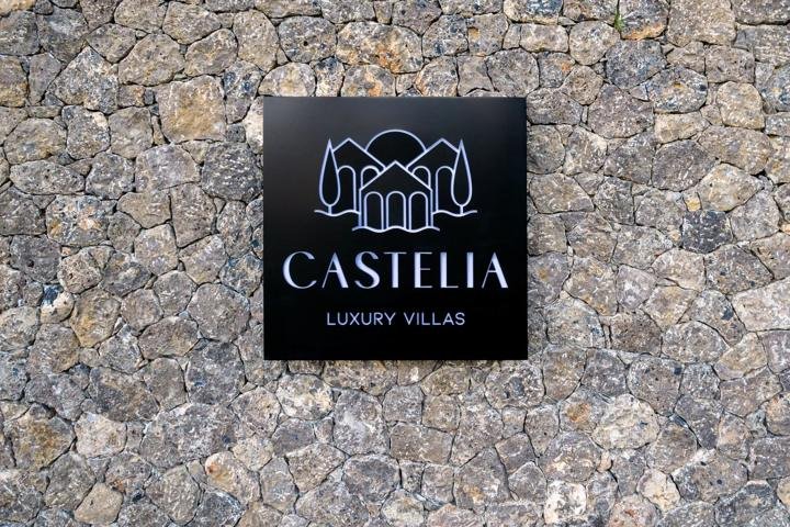 Η πινακίδα Castelia Luxury Villas στον πέτρινο τοίχο της εισόδου